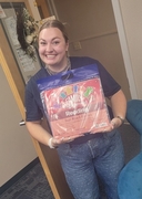 An ESU 13 staff member smiles while holding a packaged Family Engagement Reading kit.